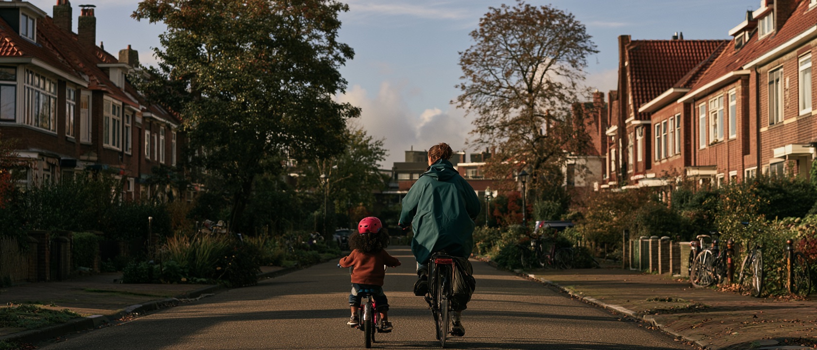 Volwassene en kind fietsen samen door een woonwijk